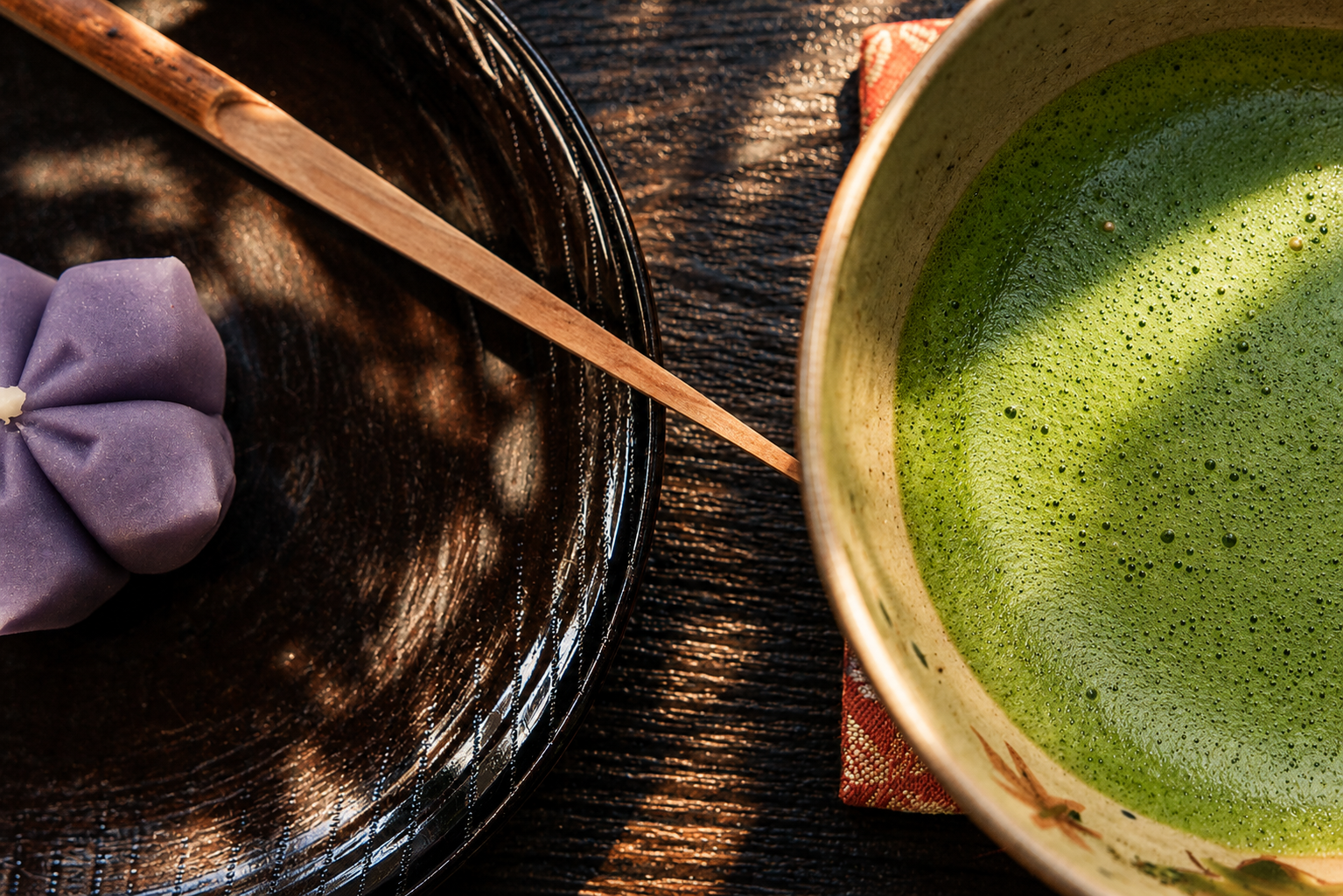 Close-up of a matcha tea bowl with a flower-shaped wagashi sweet